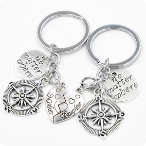 Detail of silver mother daughter split heart and compass keychains with engravings