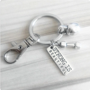 Macro shot of silver fitness keychain with dumbbell, kettlebell and inspirational plaque