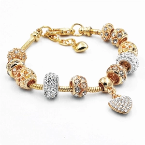 Dettaglio del bracciale con ciondoli in cristallo dorato, pendente a cuore e catena