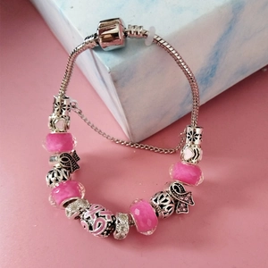 Détails d'un bracelet en perles de cristal violet avec breloques argentées et ruban rose