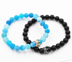 Détail des breloques couronne sur les bracelets de couple en agate et pierre noire