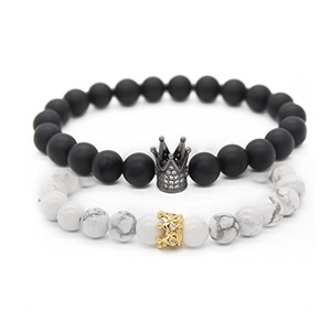 Détail de perles noires mates et marbre blanc avec des charmes de couronne brillants