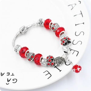 Dettaglio di un bracciale a catena snake con cristalli rossi e charm a cuore