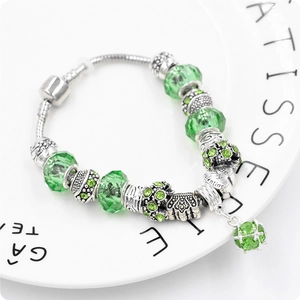 Dettaglio delle perle di cristallo verde e ciondolo a cuore su bracciale d'argento