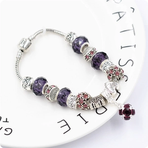 Dettaglio macro del bracciale a catena serpente con perle di vetro viola e cuore