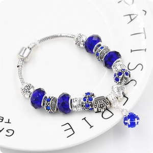 Dettaglio del bracciale a serpente con perle blu, charm corona e ciondolo a cuore