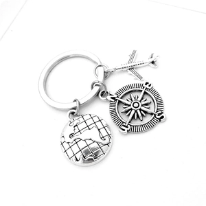 Silver travel keychain with miniature airplane, compass, and globe charms on a ring