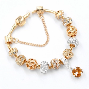 Detail of gold snake chain bracelet with hollow heart charms and amber crystal pendant