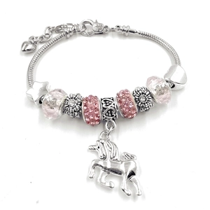 Détail de perles en cristal rose et pendentif licorne sur un bracelet maille serpent