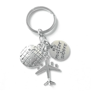 Detail of travel keychain with compass, airplane charms and engraved no matter where tag