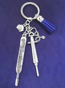 Detailed macro view of medical charms including stethoscope and blue tassel on a keychain