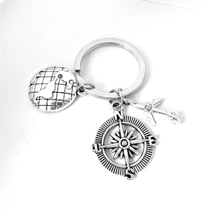Detailed macro view of silver globe, compass, and airplane charms on a travel keychain