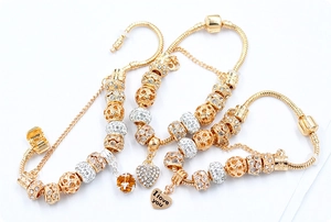 Detailed view of three gold snake chain bracelets with heart charms and crystal beads
