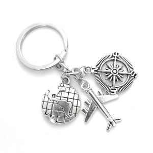 Detailed view of silver travel keychain with airplane, world map and compass charms