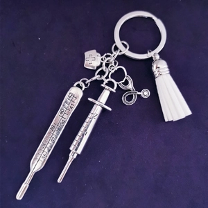 Silver medical themed keychain with syringe thermometer stethoscope and white tassel
