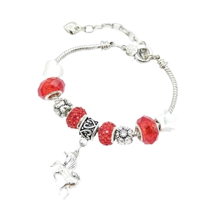 Close-up of silver snake chain bracelet with red crystal beads and unicorn pendant