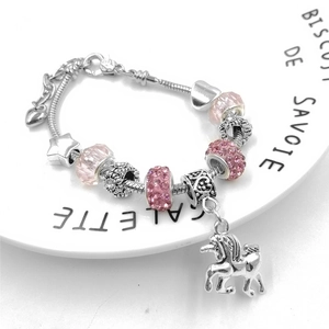Close-up of DIY charm bracelet with pink crystal beads and unicorn star pendant on a tray