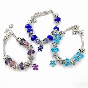 Three Pandora-style charm bracelets with purple, blue, and crystal beads on a white surface
