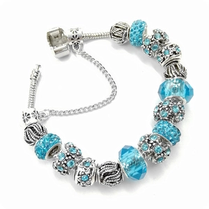 Détail macro du bracelet maille serpent argenté avec perles en cristal bleu et couronne
