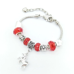 DIY charm bracelet with red glass beads, unicorn pendant, and star charm on snake chain