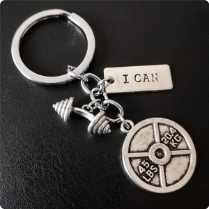 Détail du porte-clés haltère en argent avec plaque gravée I CAN sur fond en cuir