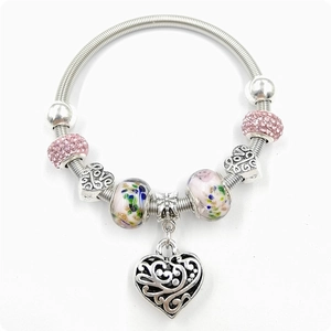 Détail du bracelet à breloques avec strass roses, perles florales et pendentif coeur
