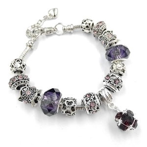 Dettaglio macro del braccialetto con ciondoli DIY, cristalli viola e pendente rosso