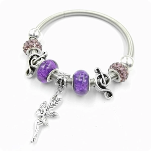 Detailed macro view of DIY charm bracelet featuring fairy pendant and purple glass beads
