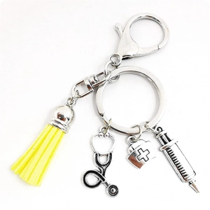 Gros plan d'un porte-clés médical en argent avec pompon jaune et breloques infirmière