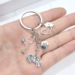 Porte-clés médical en argent avec breloques stéthoscope et ambulance tenues en main