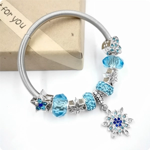 Silver snake chain bracelet with blue crystal beads and snowflake charms on white background
