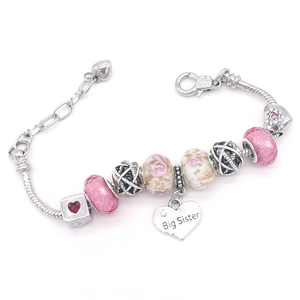 Détail d'un bracelet à chaîne serpent argentée avec breloque Big Sister et perles roses