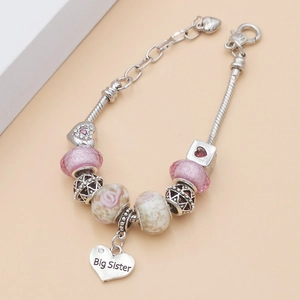 Détail du bracelet rose à breloques avec pendentif coeur gravé Big Sister