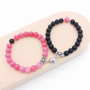 Primo piano dei braccialetti magnetici per coppie con perle rosa, nere e chiusura a cuore