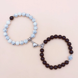 Dettaglio di bracciali per coppia in perline nere e bianche con chiusura magnetica