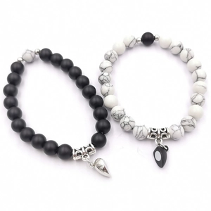 Dettaglio dei ciondoli a cuore magnetici su braccialetti di perline turchesi bianche e nere