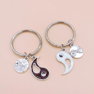 Detail of pinkie swear and yin yang pendants on silver couple keychains for friends