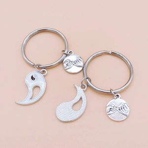 Detail of Yin Yang keychains with pinky swear charms on soft pink background