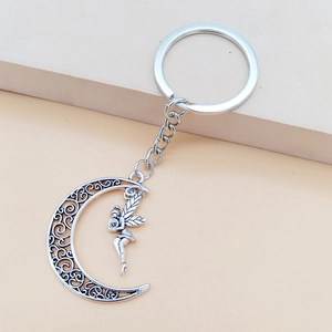Close-up of vintage silver fairy pendant with hollowed moon charm on metal keychain