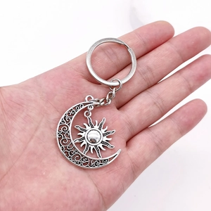 Macro detail of antique silver sun and moon keychain with hollow moon and radiant sun pendant