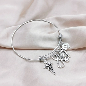 Detail view of medical charms on silver stainless steel bracelet over silk background