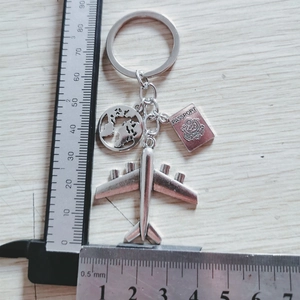 Silver alloy keychain with airplane, passport, and globe charms for travel lovers