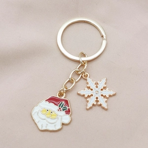 Festive gold Christmas keychain with Santa Claus and snowflake charms on pink background
