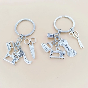 Portachiavi vintage in metallo argento con macchina da cucire e forbici su beige