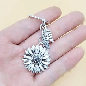 Close-up of vintage silver sunflower keychain with detailed leaves held in hand