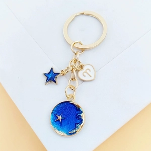 Détail du porte-clés Bélier avec pendentifs étoile et lune en émail bleu sur anneau doré
