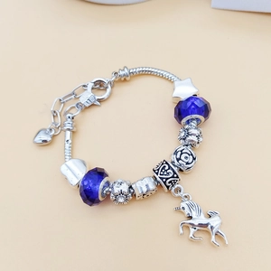 Detailansicht eines silbernen Schlangenarmbands mit blauen Glasperlen und Einhorn-Anhänger