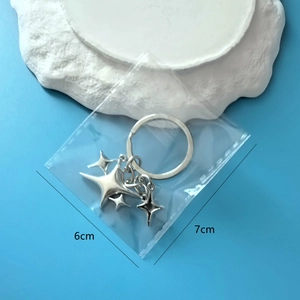 Porte-clés étoile à quatre branches en argent avec breloques dans un sachet 6x7cm