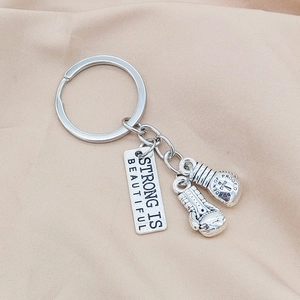 Zilveren bokshandschoenen sleutelhanger met Strong Is Beautiful en Never Give Up tekst