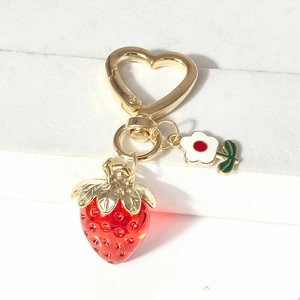 Détail du porte-clés fraise avec fermoir coeur doré et pendentif fleur sur le bureau